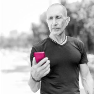 Ein älterer Mann guckt auf sein Handy in der Hand.