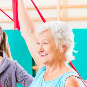 Eine lachende ältere Frau, die Gymnastik mit einem Terraband macht